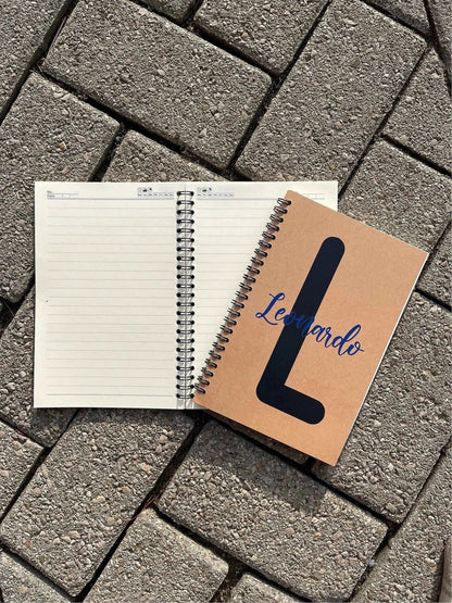Personalized soft cover spiral notebook with kraft cover, 8 x 5.5 inches, open on a stone surface.