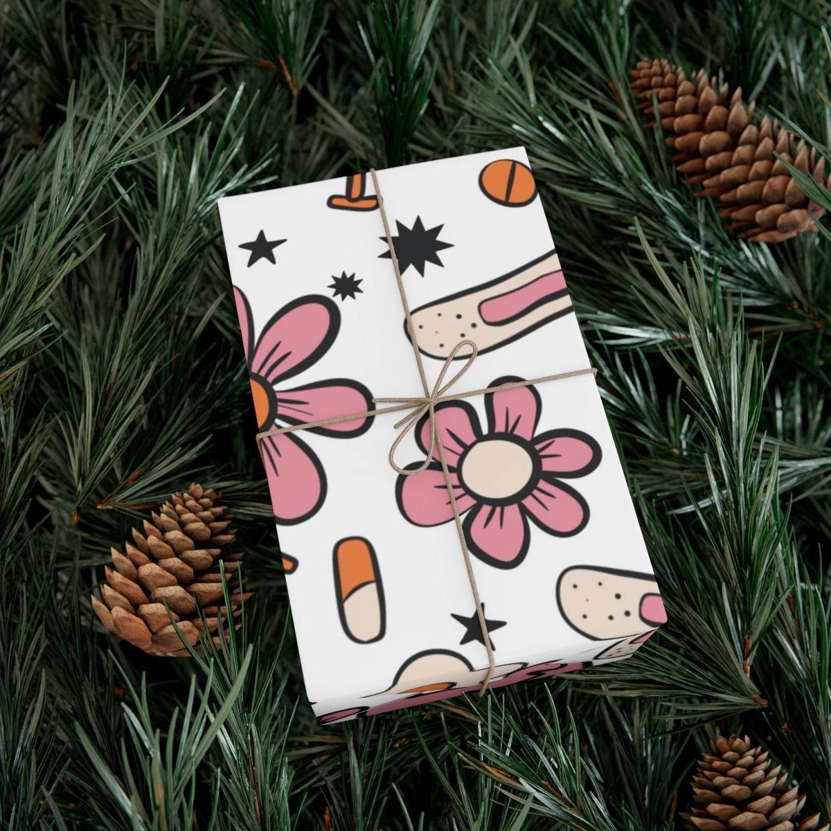 Nurse themed wrapping paper with flowers, bandages, and medication patterns on a gift box surrounded by pine branches.
