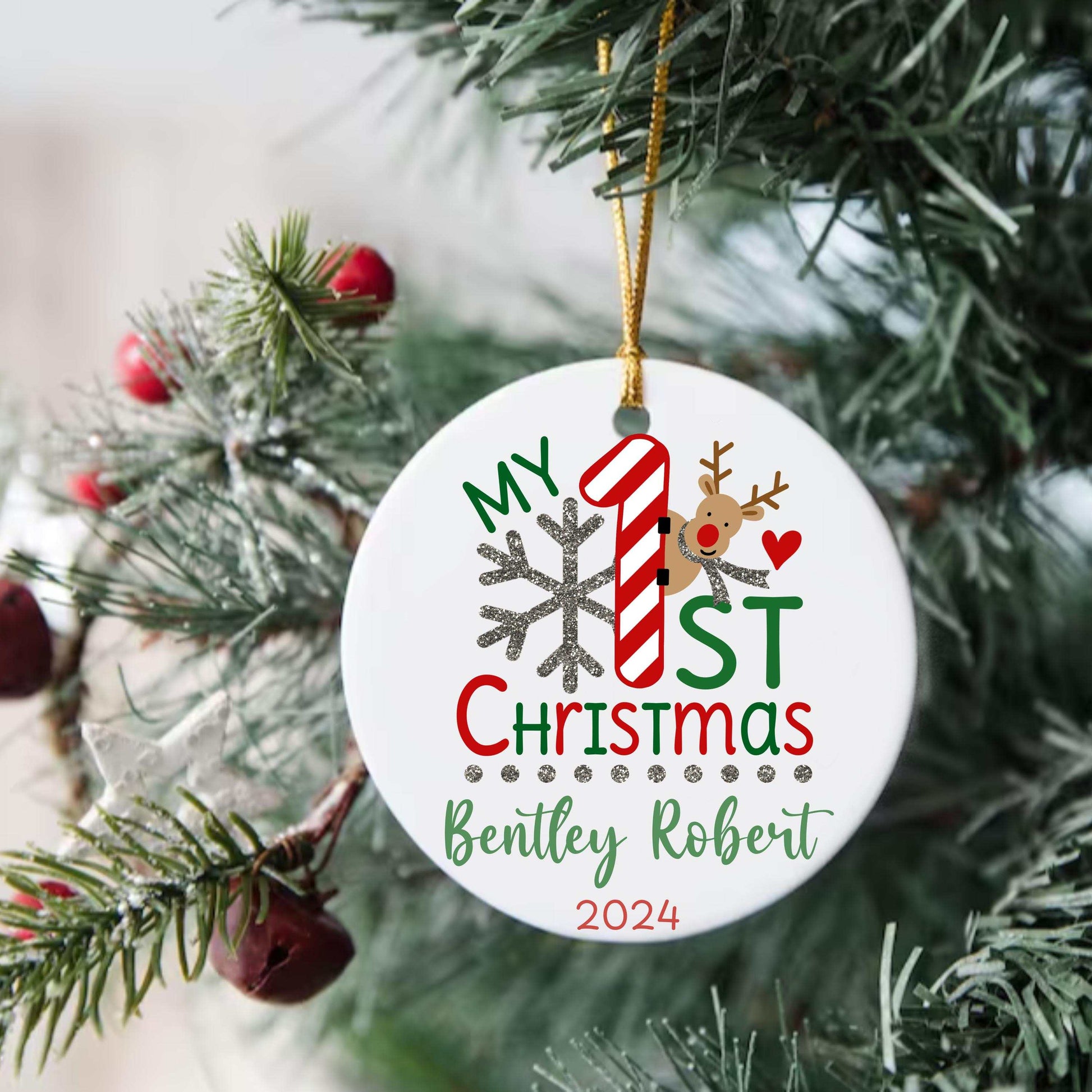Personalized ceramic baby ornament for first Christmas with name, date, candy cane, reindeer, and snowflake design hanging on tree.