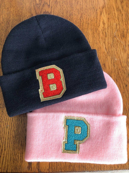 Custom embroidered initial beanies in black and pink with fold-over design for kids and adults.