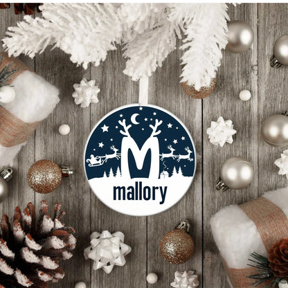Monogrammed Christmas ornament with a reindeer scene and the name Mallory hanging on a white tree branch
