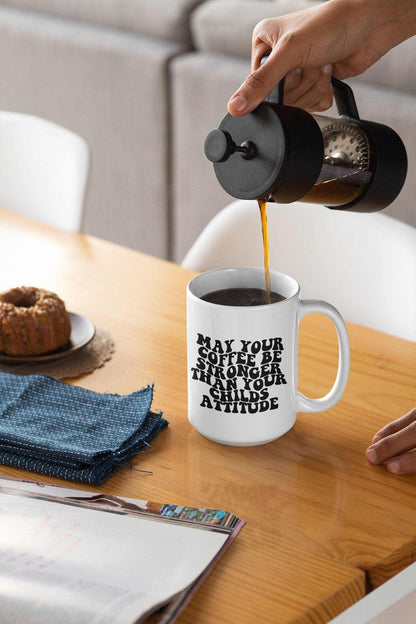 Funny sayings ceramic coffee mug with "May Your Coffee Be Stronger Than Your Child's Attitude" text, 15oz size.