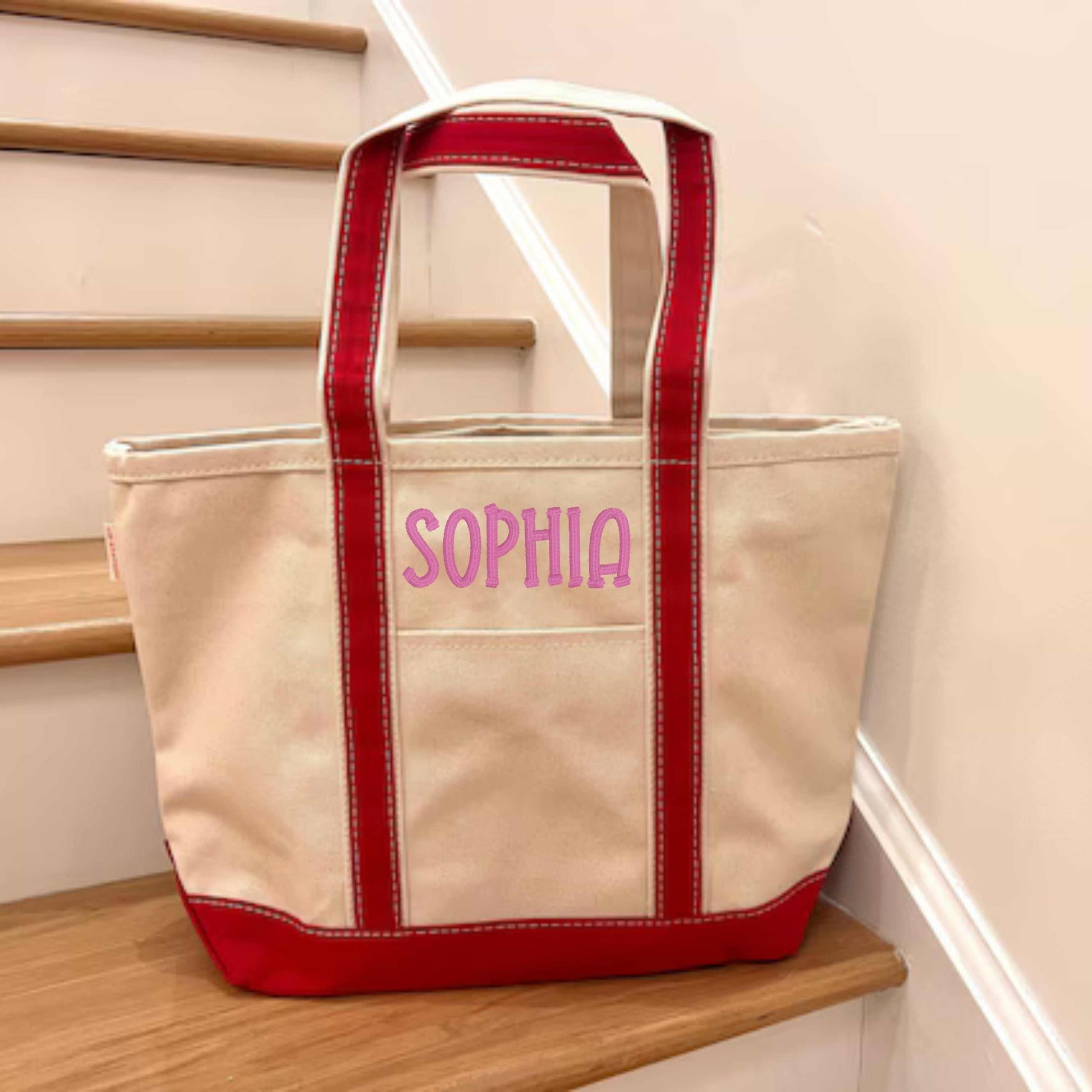 Red strap canvas tote with embroidered name on pocket, eco-friendly and durable.