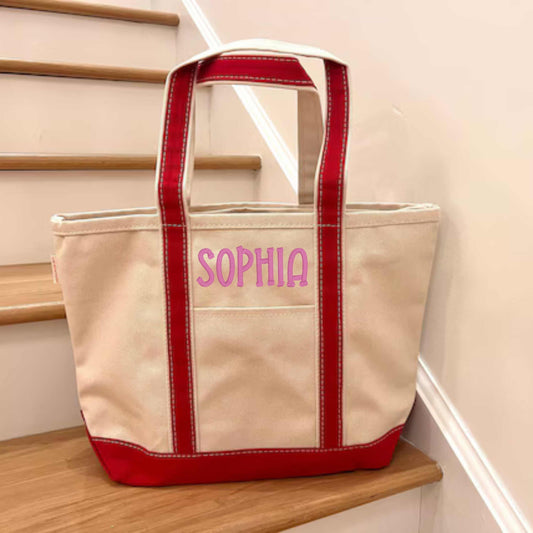 Red strap canvas tote with embroidered name on pocket, eco-friendly and durable.