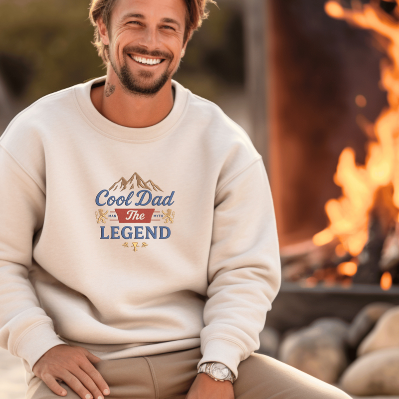 Man wearing a sweatshirt with 'Cool Dad The Legend' text by a campfire