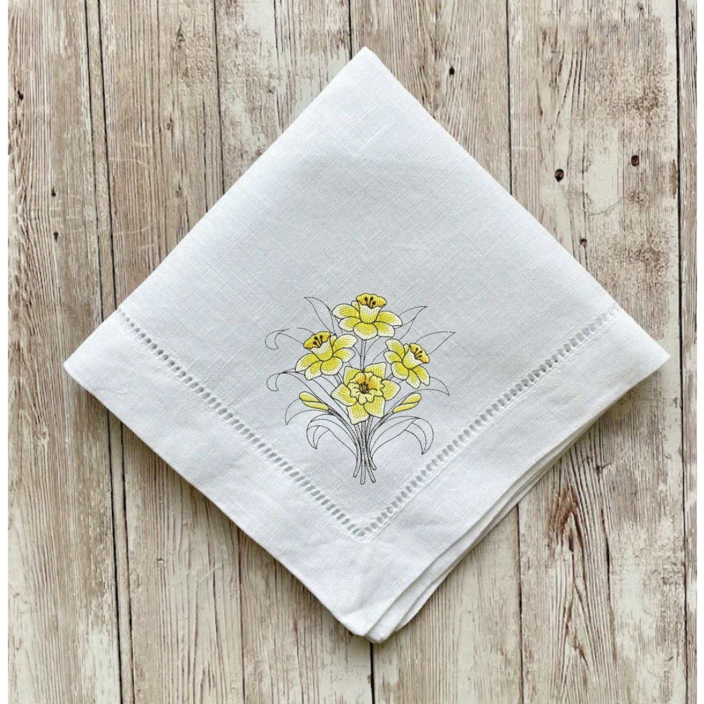 Nature-themed reusable cloth napkin with floral botanical design, intricate hemstitch, in cream, linen-cotton blend.