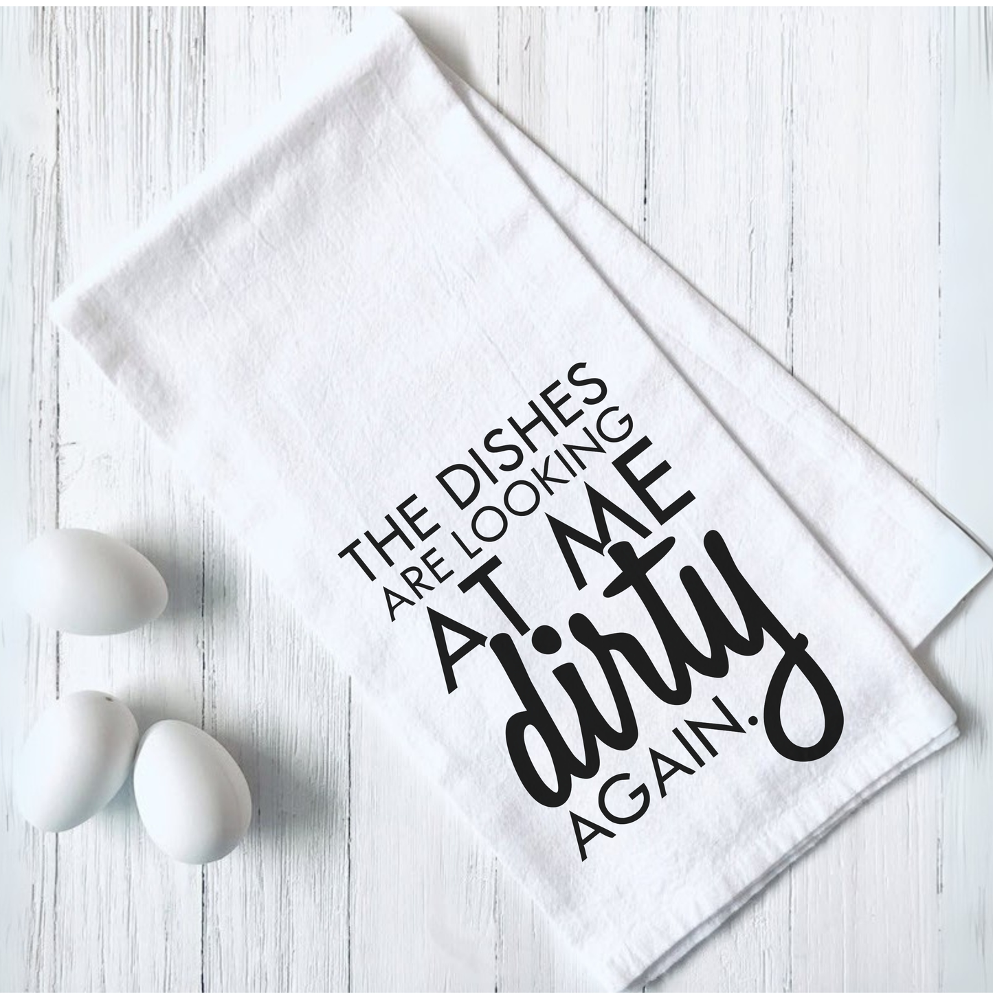 Funny tea towel with "The Dishes are Looking at Me Dirty Again" text design on white fabric