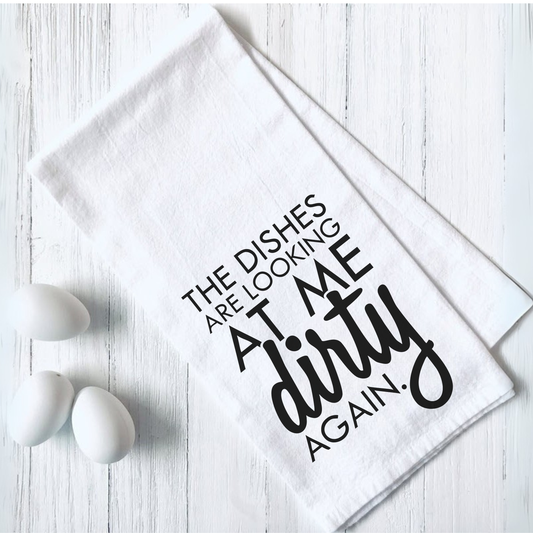 Funny tea towel with "The Dishes are Looking at Me Dirty Again" text design on white fabric
