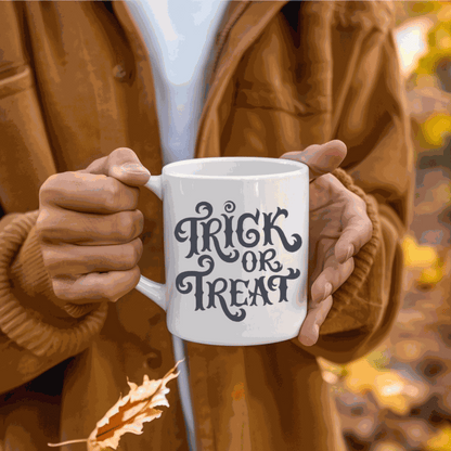 Halloween-themed ceramic mug with "Trick or Treat" design held by person in autumn setting.