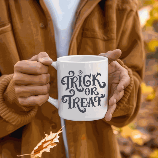 Halloween-themed ceramic mug with "Trick or Treat" design held by person in autumn setting.