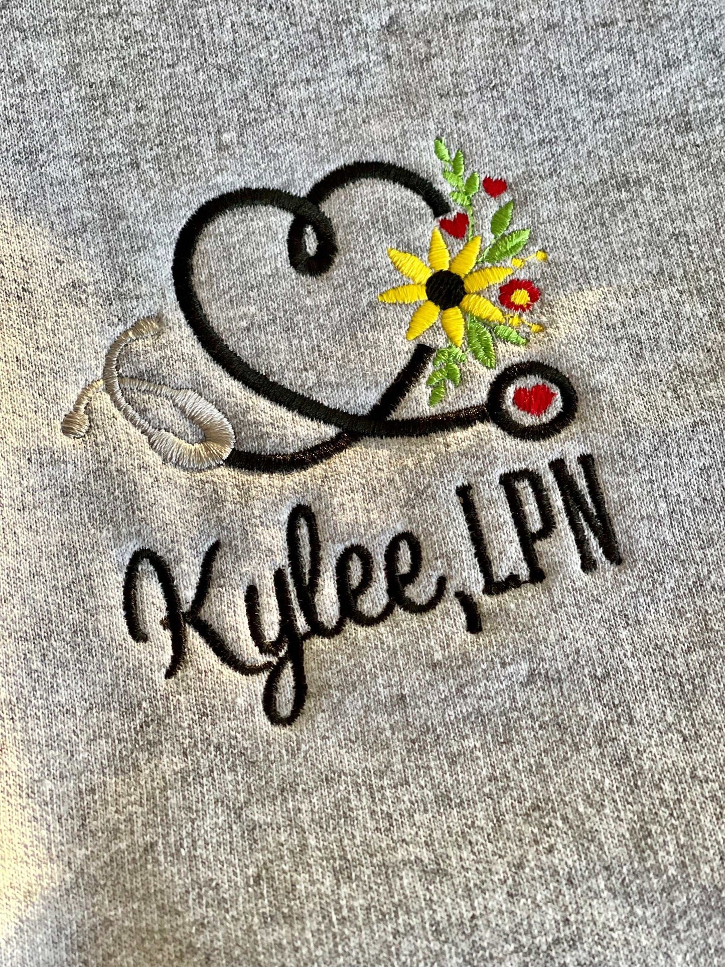 Embroidered nurse sweatshirt with stethoscope and floral heart design, personalized with "Kylee, LPN".
