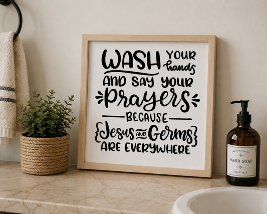 Bathroom counter with framed sign, plant, and hand soap bottle.
