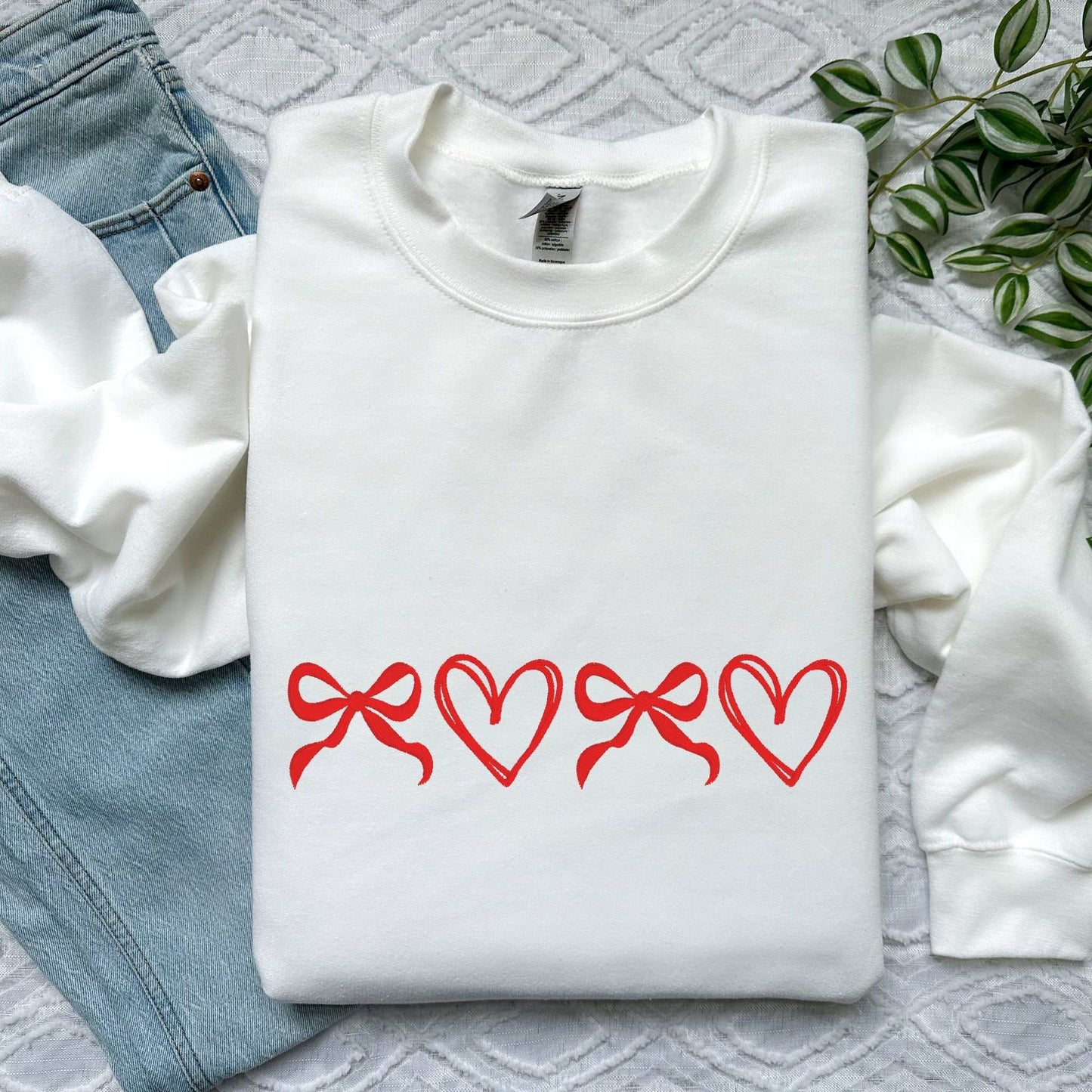 Custom coquette sweatshirt with red bow and heart embroidery on white fabric, perfect Valentine’s or Mother’s Day gift.