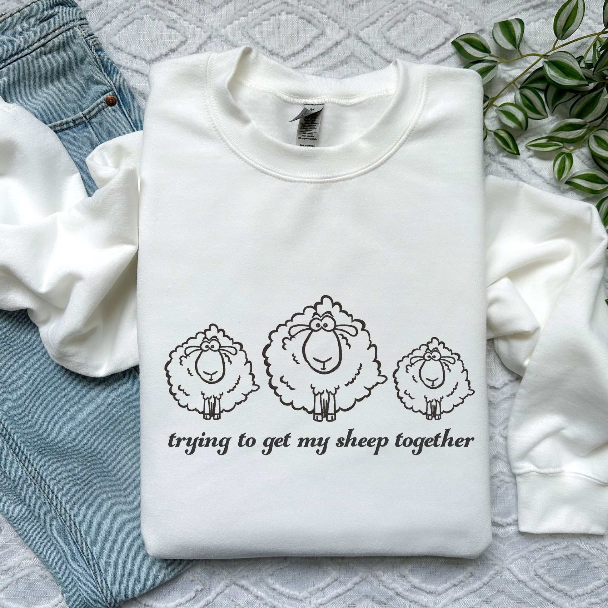 Cozy embroidered sweatshirt featuring three fluffy sheep and the phrase "Trying to Get My Sheep Together," perfect for
