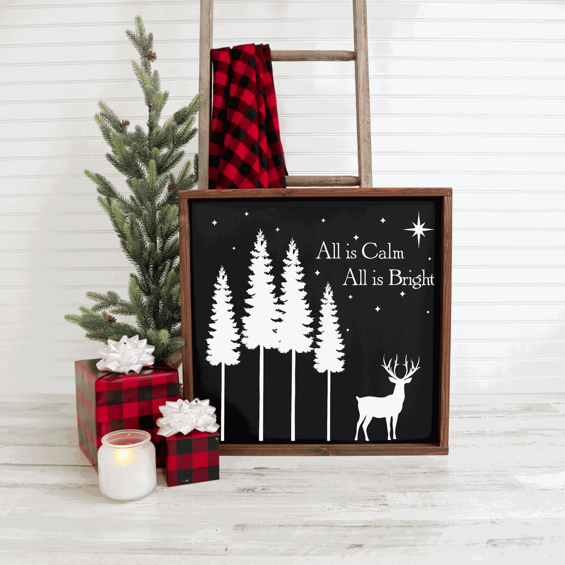 Handmade Christmas wood sign with "All is Calm, All is Bright" design, featuring white lettering on a black background, next to festive decor.