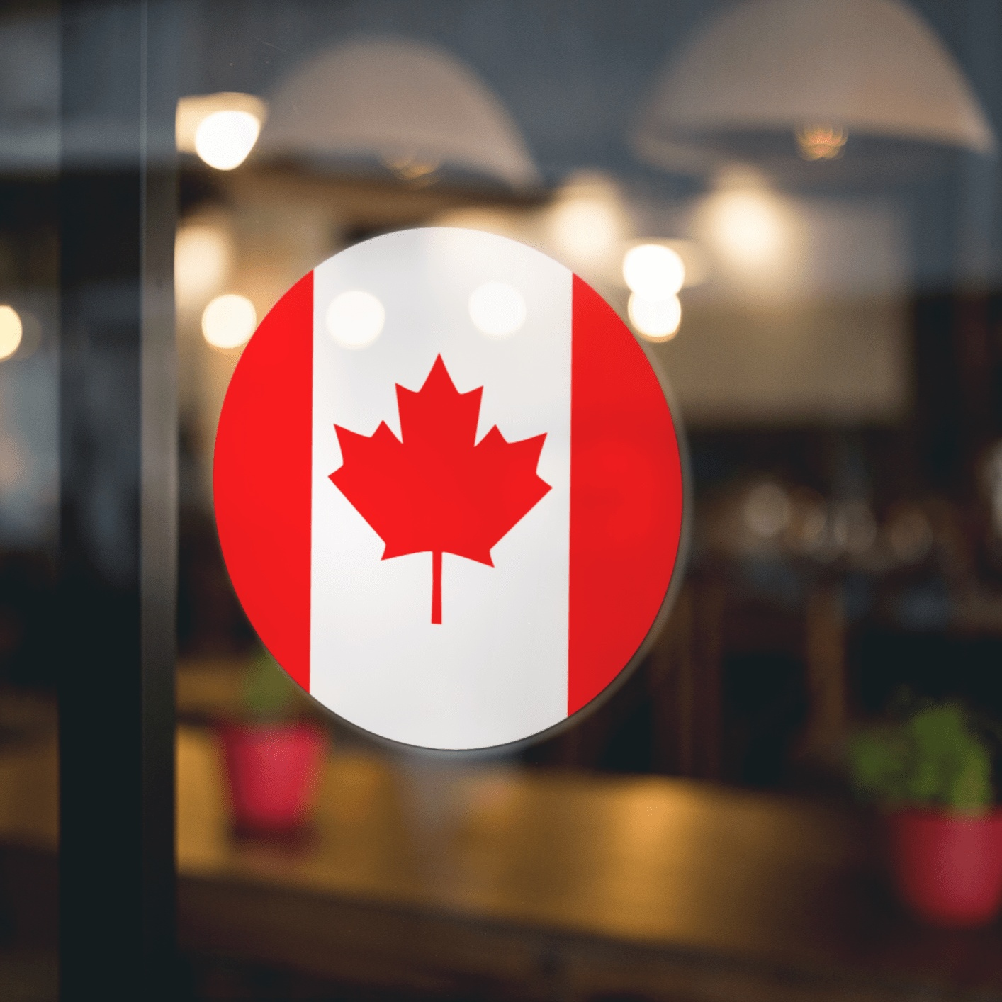 Canada Flag Sticker on glass window, showcasing red maple leaf design; ideal for laptops, cars, and more; made of durable vinyl.