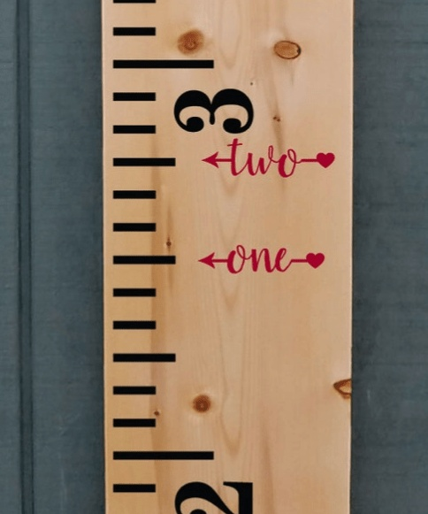 Height marker decals on wooden growth chart ruler.