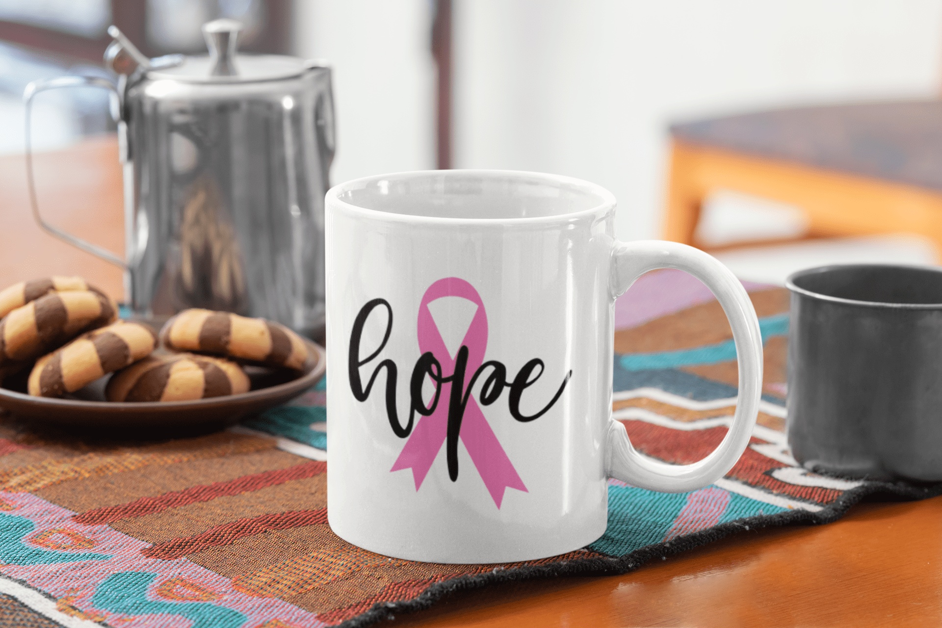 Hope and Pink Ribbon decal on a white mug, displayed on a colorful table setting with cookies and a teapot in the background.