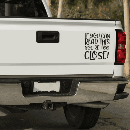 Car decal with quote "If you can Read This You are too Close!" on a white truck tailgate.