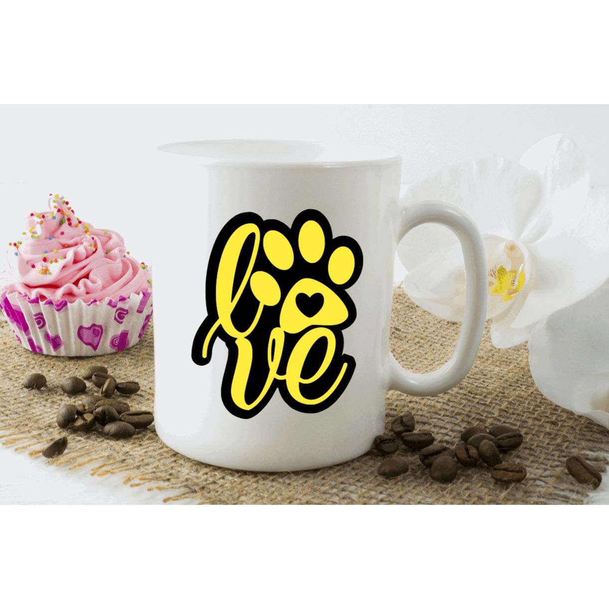 Yellow love dog paw monogram decal on white mug with sweets and coffee beans.