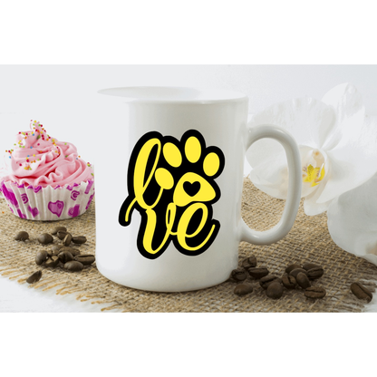 Yellow love dog paw monogram decal on white mug with sweets and coffee beans.