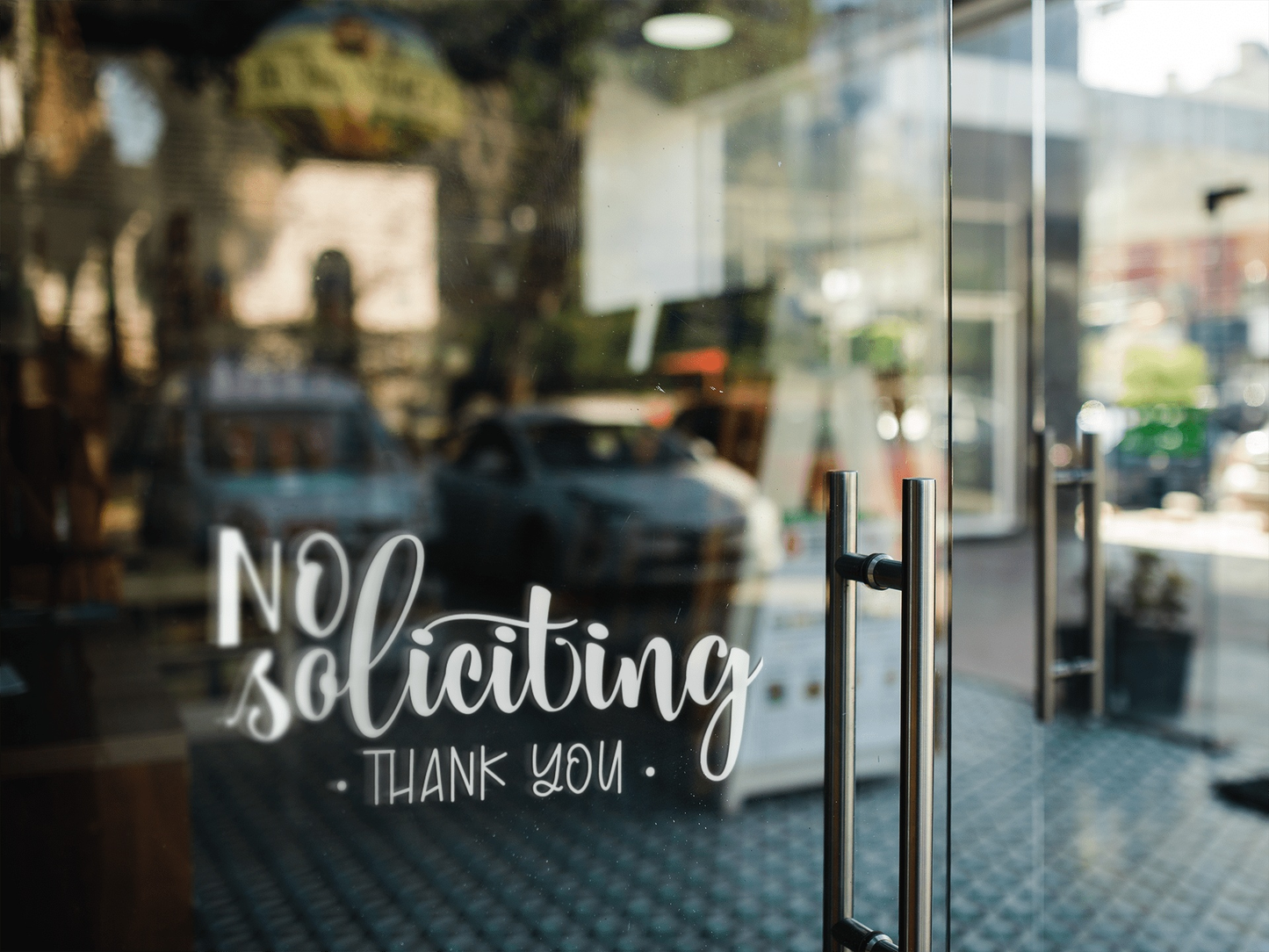 No Soliciting vinyl door decal on glass door with street view in background.