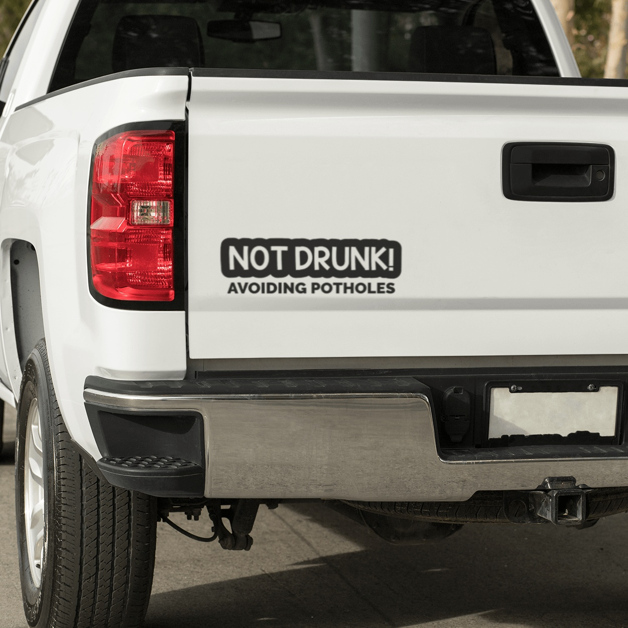 Not Drunk Avoiding Potholes car sticker on a white truck tailgate.