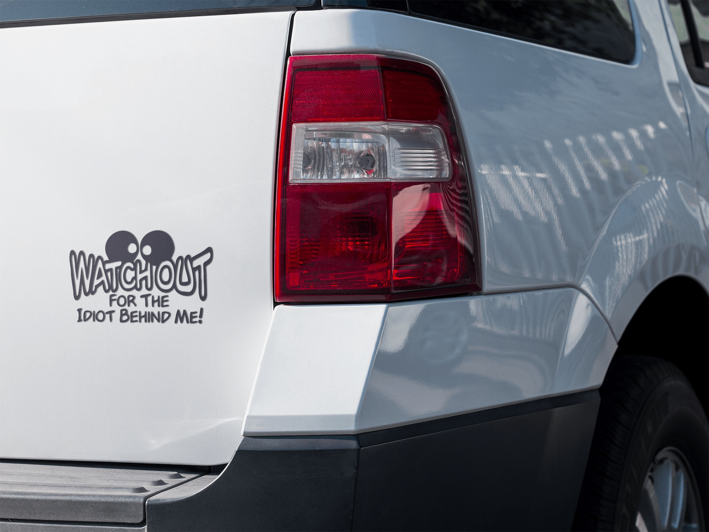 Car decal reading "Watchout for the Idiot Behind Me" on a vehicle's rear.