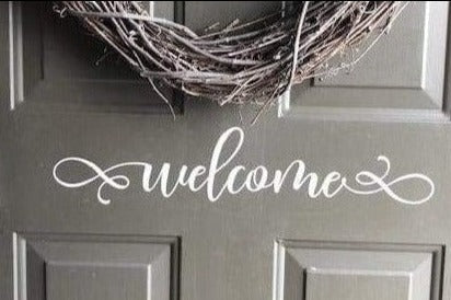 Decorative vinyl "Welcome" door decal on a grey front door with wreath.