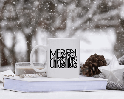 White ceramic mug with "Merry Christmas" design, snow background, pinecones, and candle.