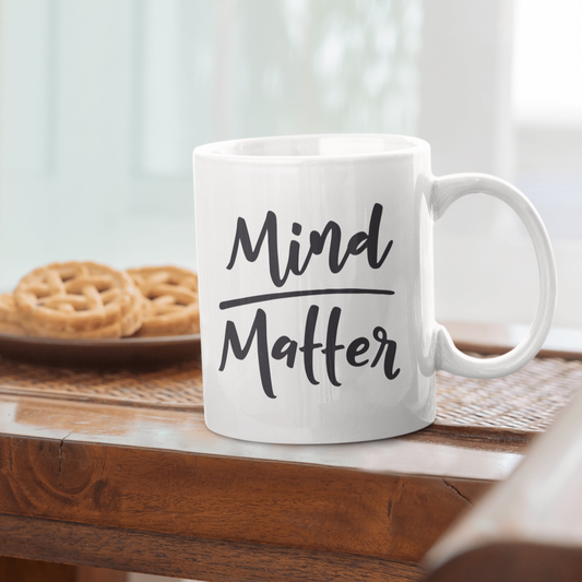 Inspirational mug with "Mind over Matter" saying on a wooden table.