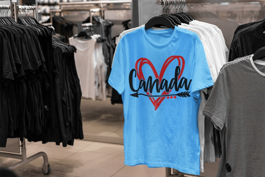 Blue Canadian T-shirt with red heart design displayed in a store.