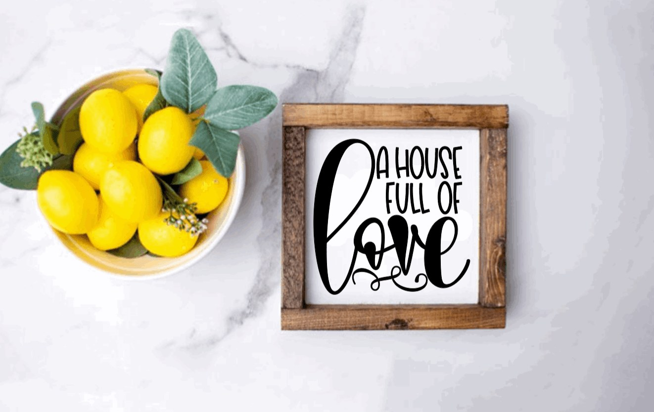 Handmade wood sign reading "A House Full of Love" with rustic frame on marble surface.