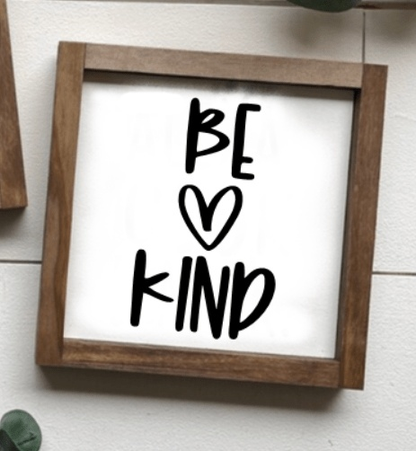 Handmade "Be Kind" sign with natural wood frame and black lettering on a white background.