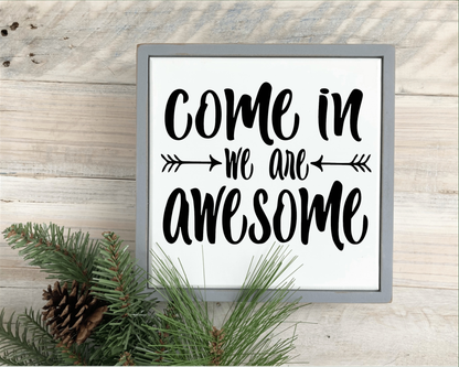 Wood sign with "Come in We Are Awesome" in black lettering on a white background, gray frame.