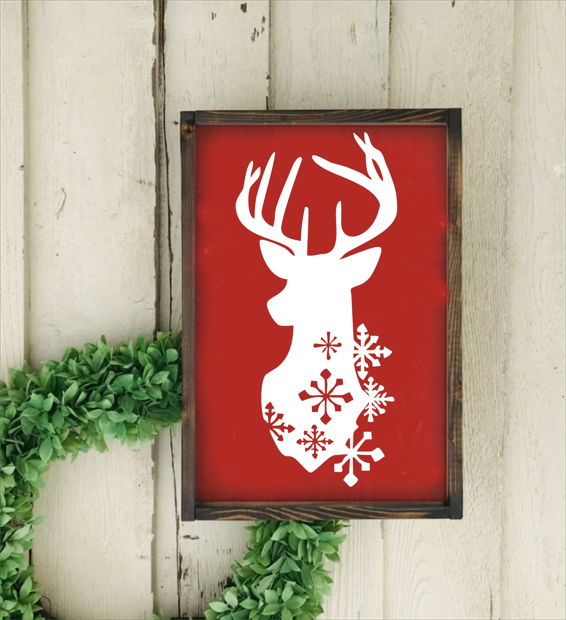 Christmas deer head with snowflakes framed handmade sign on red background with pine frame.