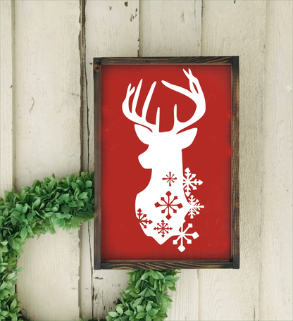 Christmas deer head with snowflakes framed handmade sign on red background with pine frame.