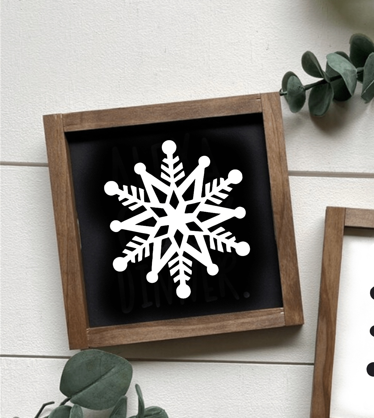 Framed snowflake shelf sitter with black background and wooden frame.