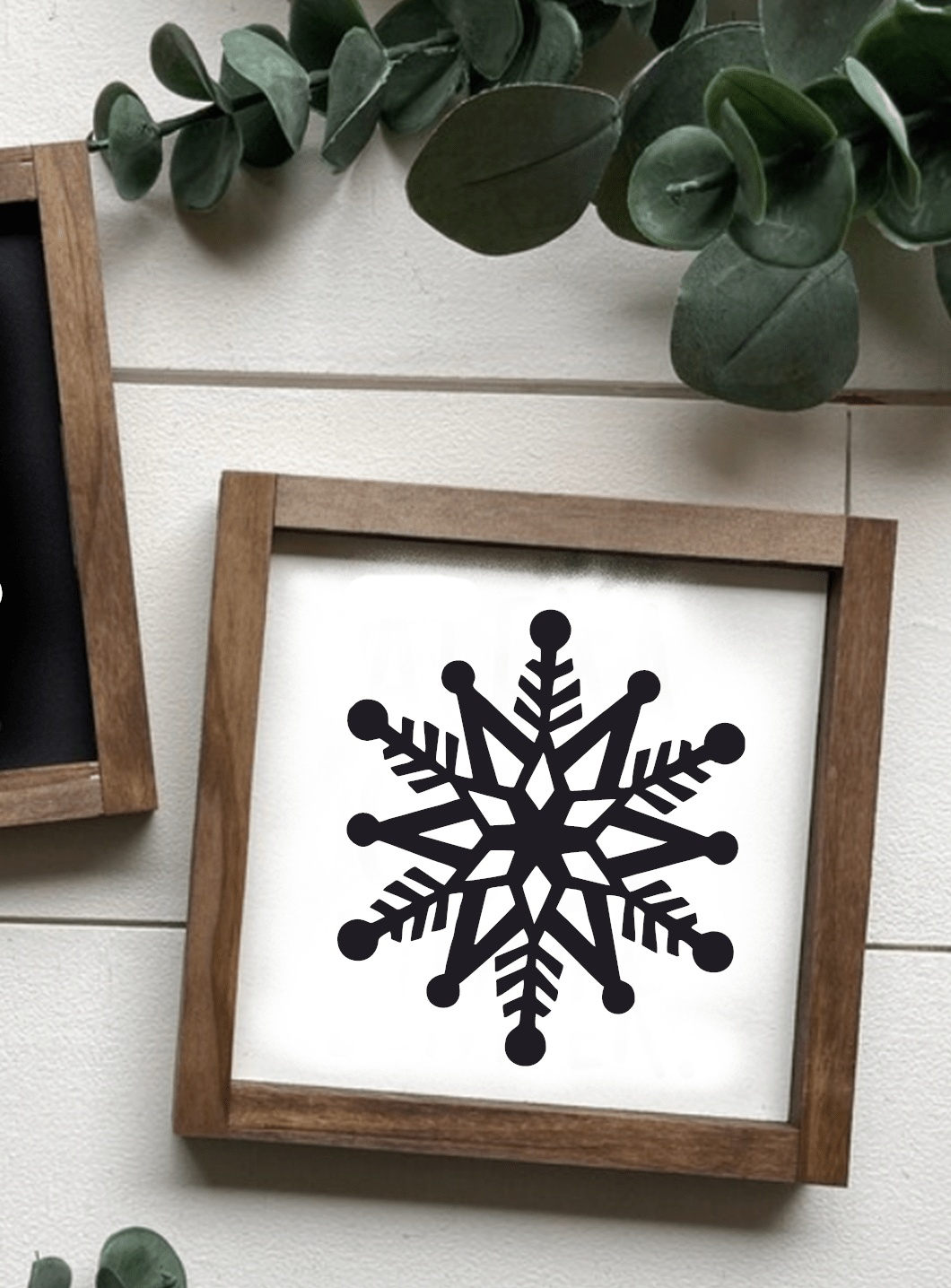Framed hand-painted snowflake shelf sitter on white background with stained wood frame.