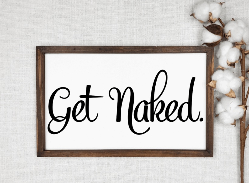 Get Naked rustic bathroom wood sign with black lettering on a white background and a wooden frame.