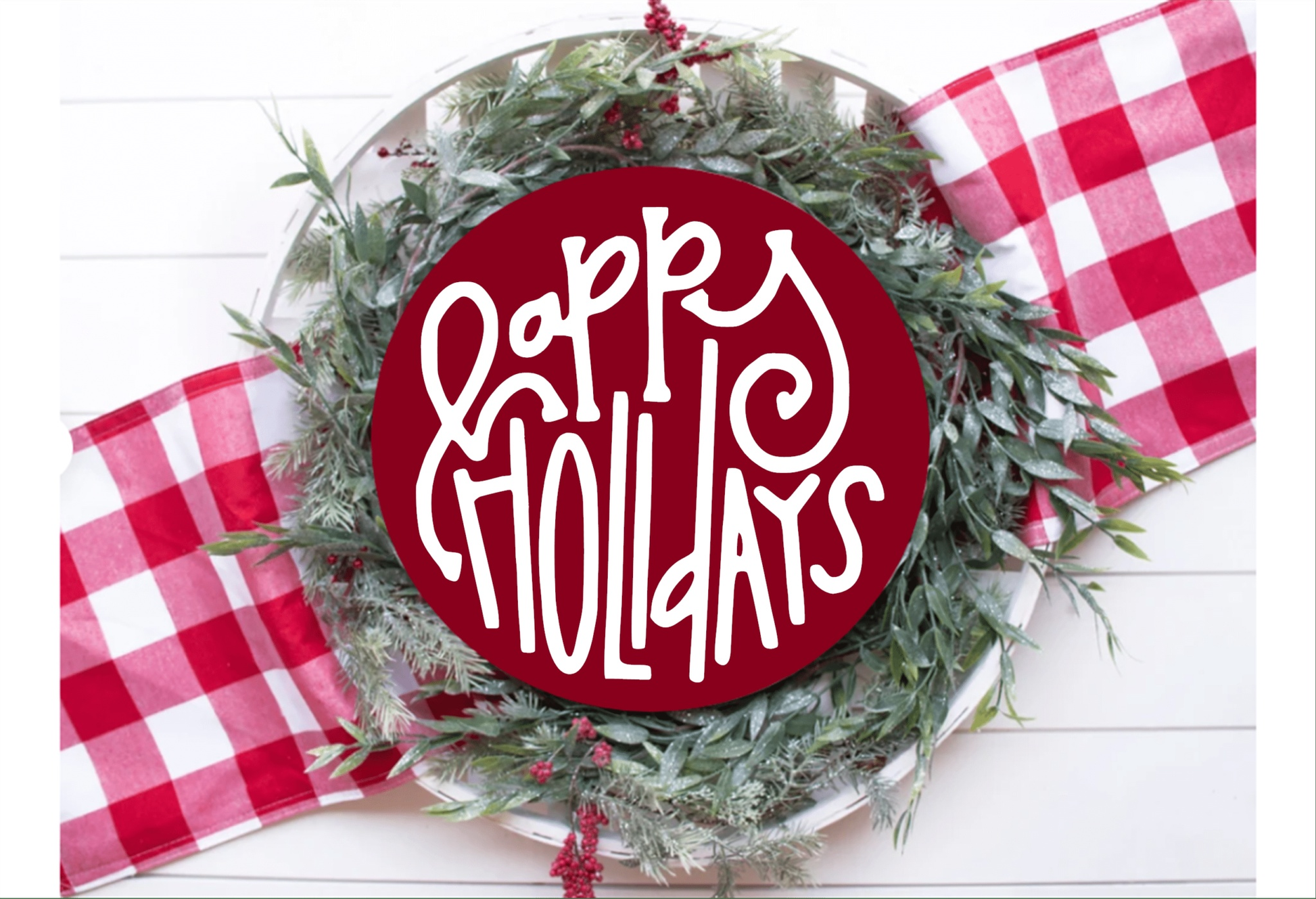 Happy Holidays wood sign with red background and white lettering, surrounded by greenery and red checkered ribbon.