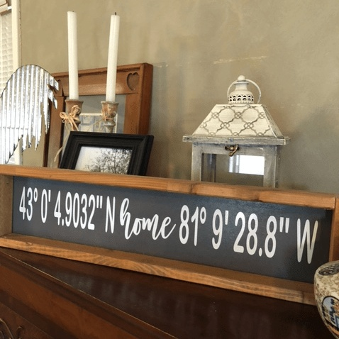 Handmade personalized home coordinates wood sign on a shelf.