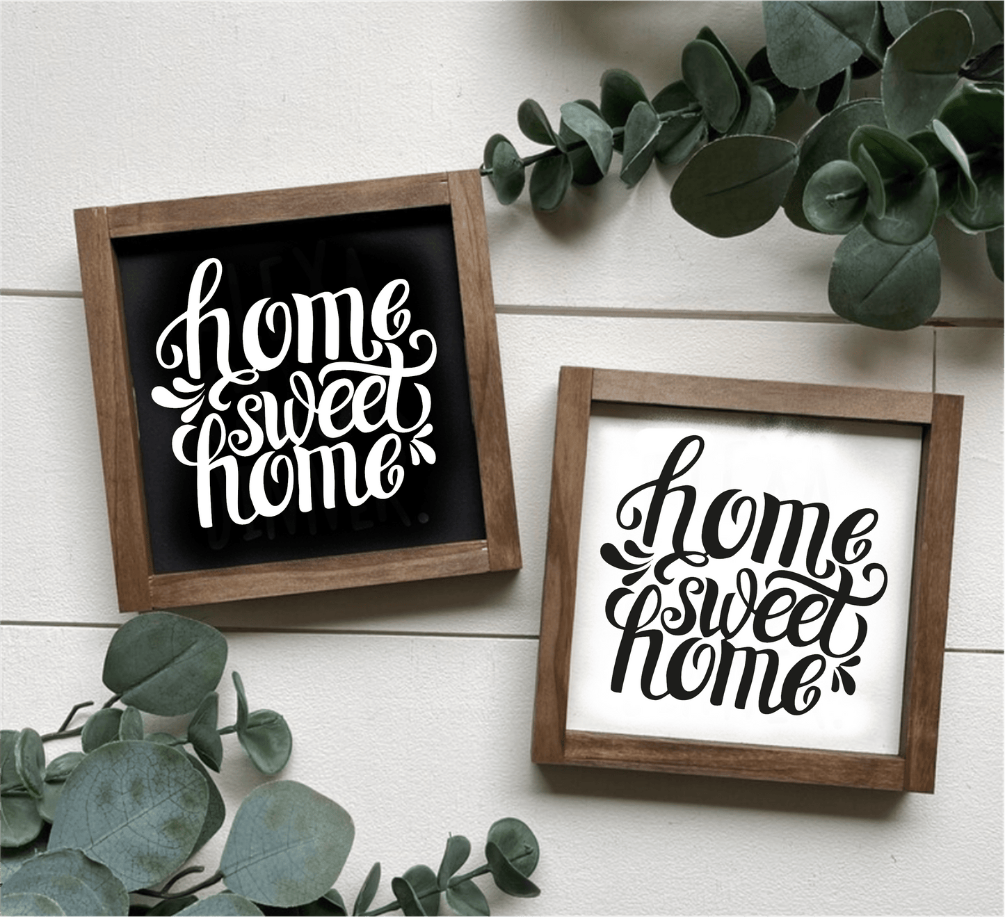 Handcrafted "Home Sweet Home" framed wood signs with white and black backgrounds and contrasting lettering, surrounded by greenery.