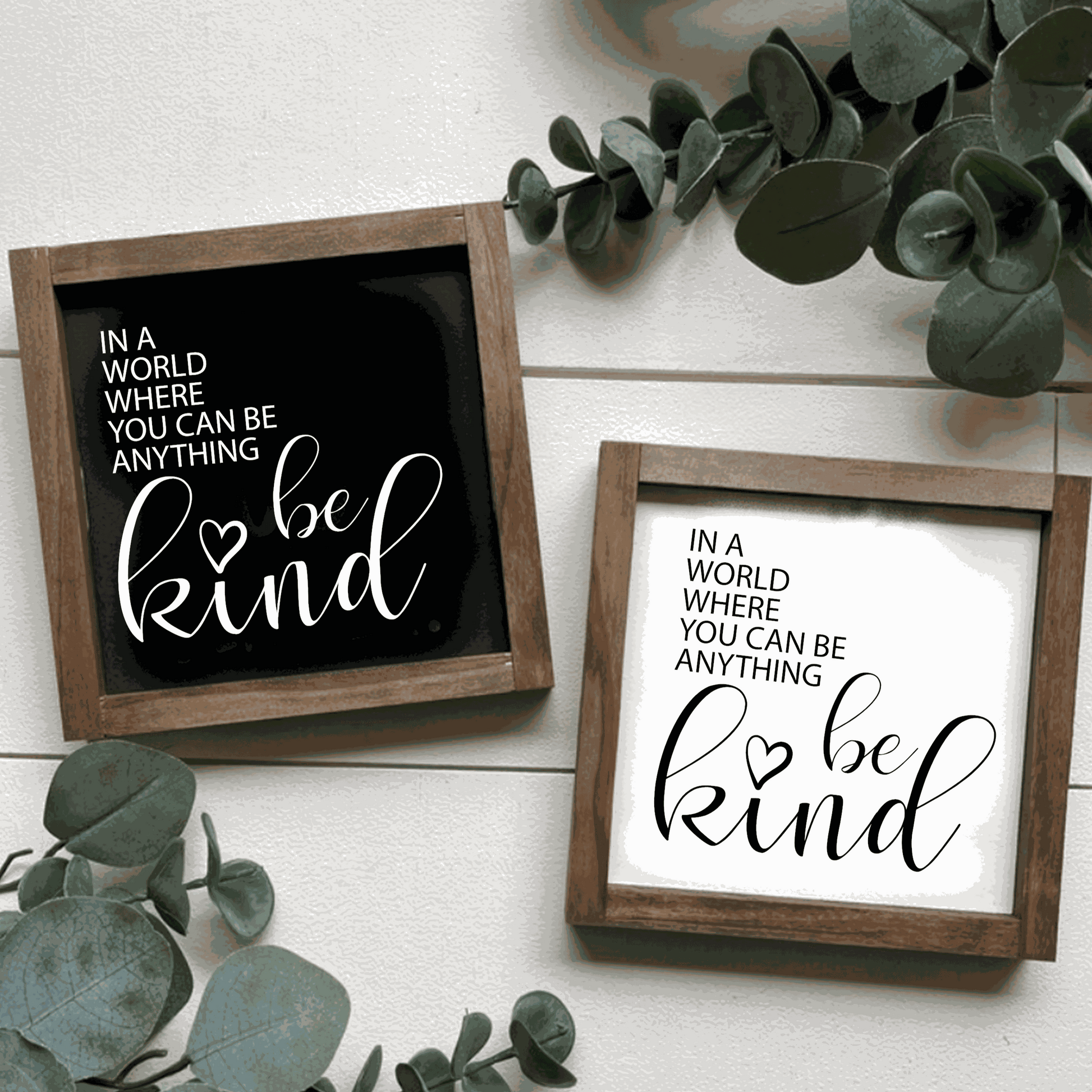 Framed wood signs with "In a World where you can be Anything Be Kind" message, in black and white backgrounds.