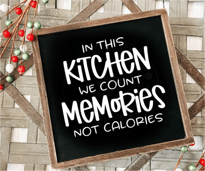 Framed wood sign with "In this Kitchen we Count Memories not Calories" on a black background.