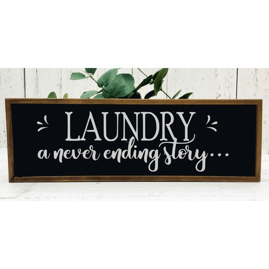 Wood framed sign with "Laundry a never ending story" text in black and white.