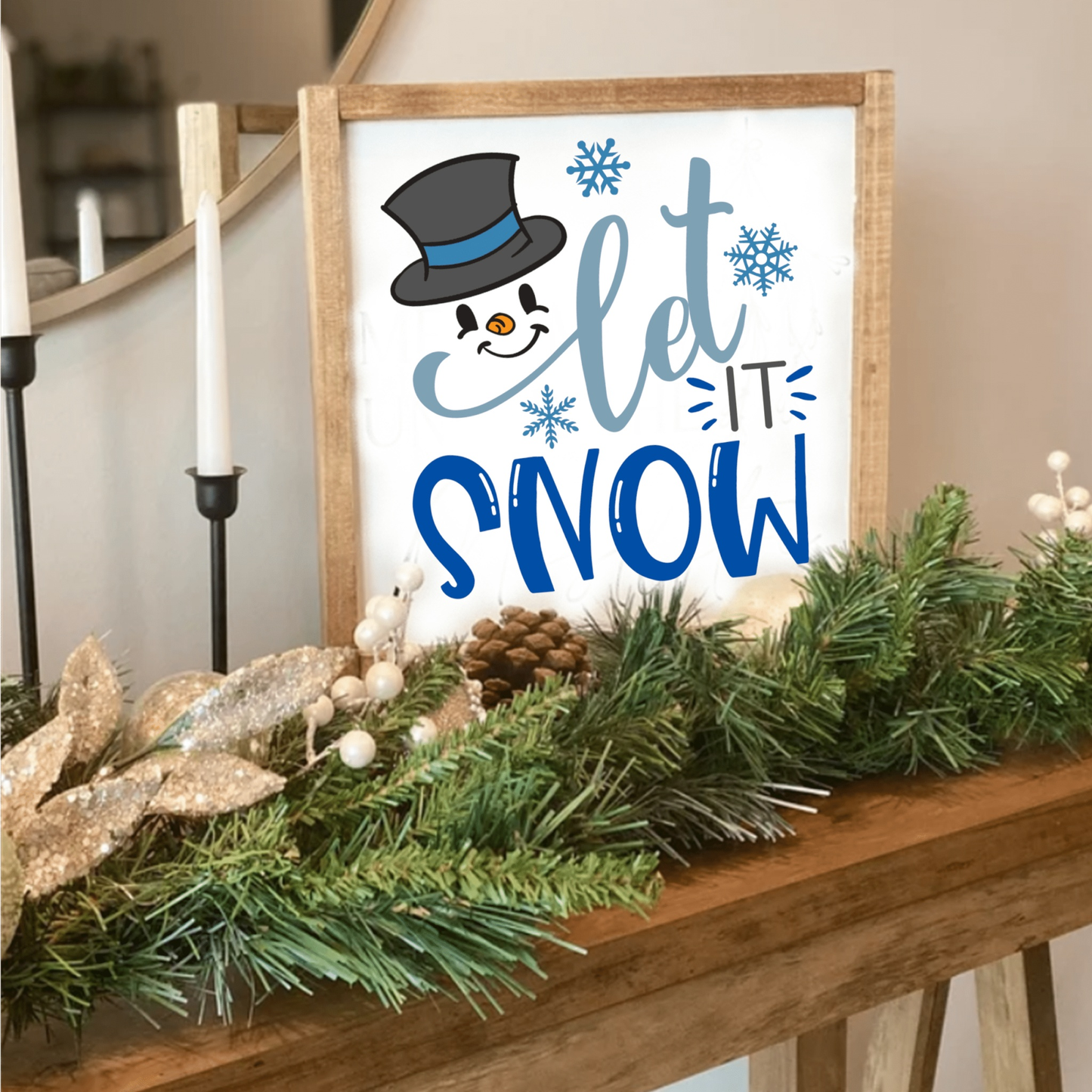 Handcrafted wood sign with snowman design and "Let it Snow" text, adorned with snowflakes, displayed on a mantle with festive greenery.