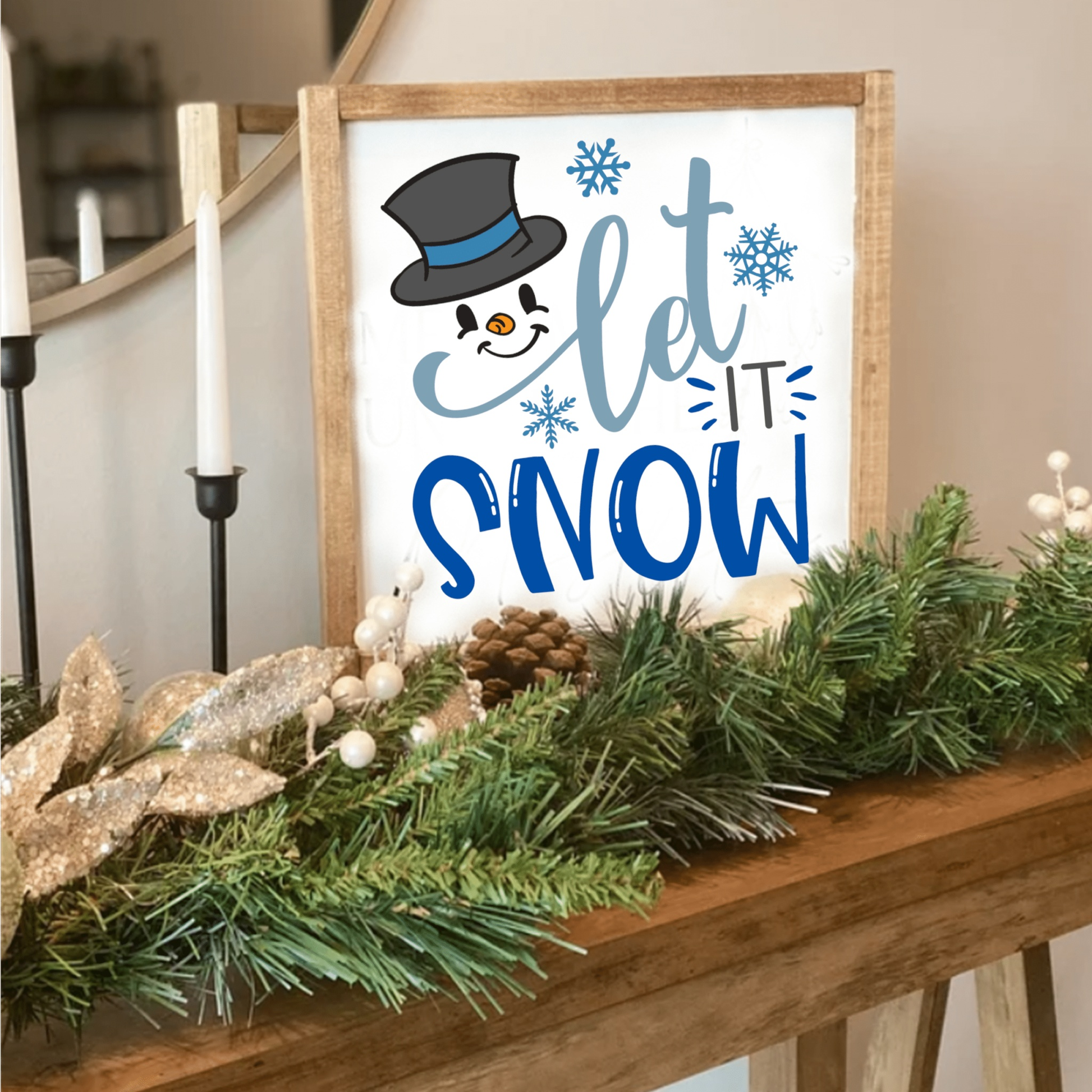 Handcrafted wood sign with snowman design and "Let it Snow" text, adorned with snowflakes, displayed on a mantle with festive greenery.