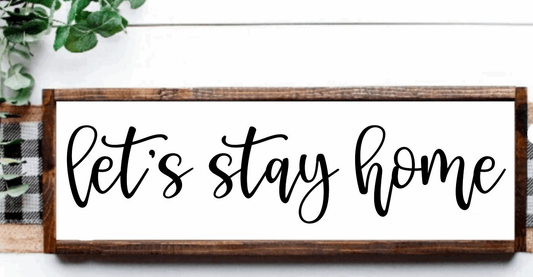 Let's Stay Home rustic wood sign with white background and black lettering, framed in stained wood.