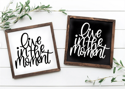 Handcrafted framed wood sign with "Live in the Moment" text in black on white and white on black backgrounds.